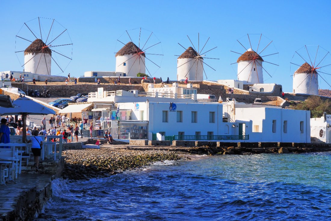 Die fünf Kato Mili Windmühlen auf der griechischen Insel Mykonos sind weiß und stehen am Meer.