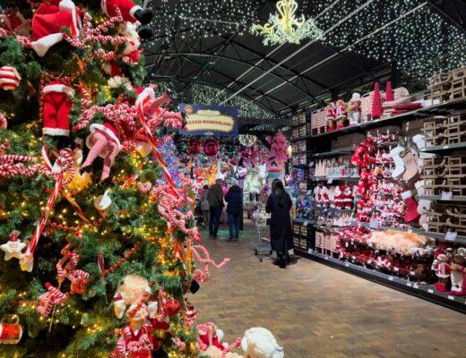 Ein riesiger Weihnachtsladen in Holland ist Leurs Venlo 2025. Abgebildet ist links ein geschmückter Weihnachtsbaum und auf der anderen Seite des Ganges steht rechts Weihnachtsdeko. Über den Einkaufenden hängt ein Kronleuchter.